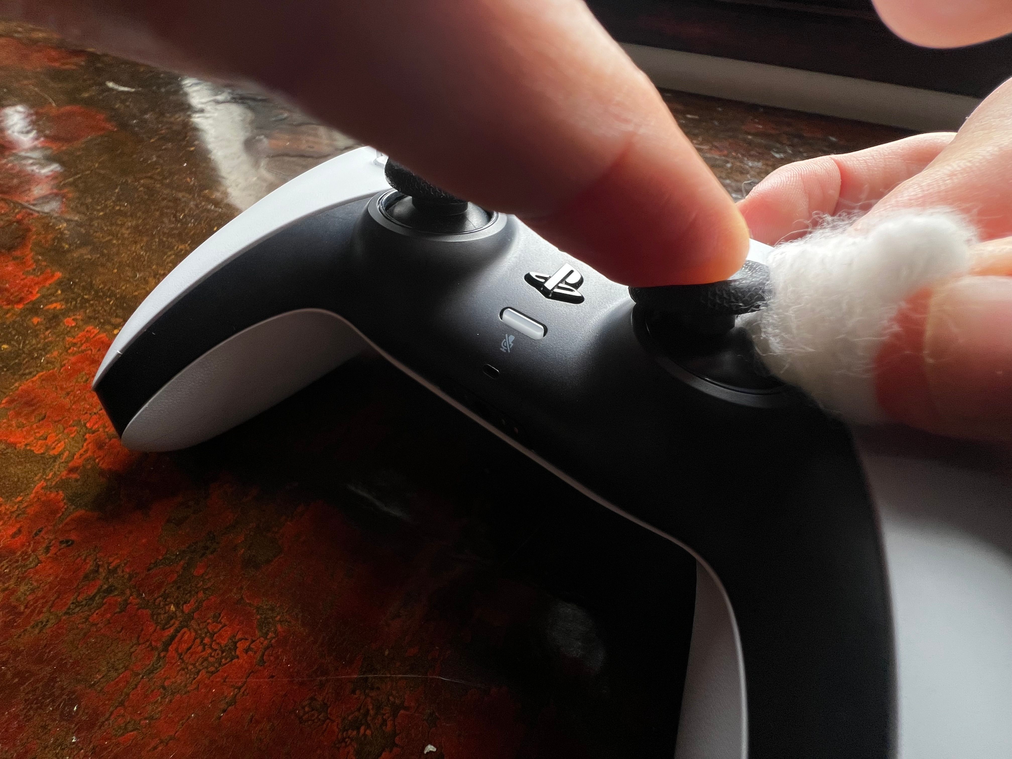Cleaning a DualSense analog stick with cotton wool and isopropyl alcohol.
