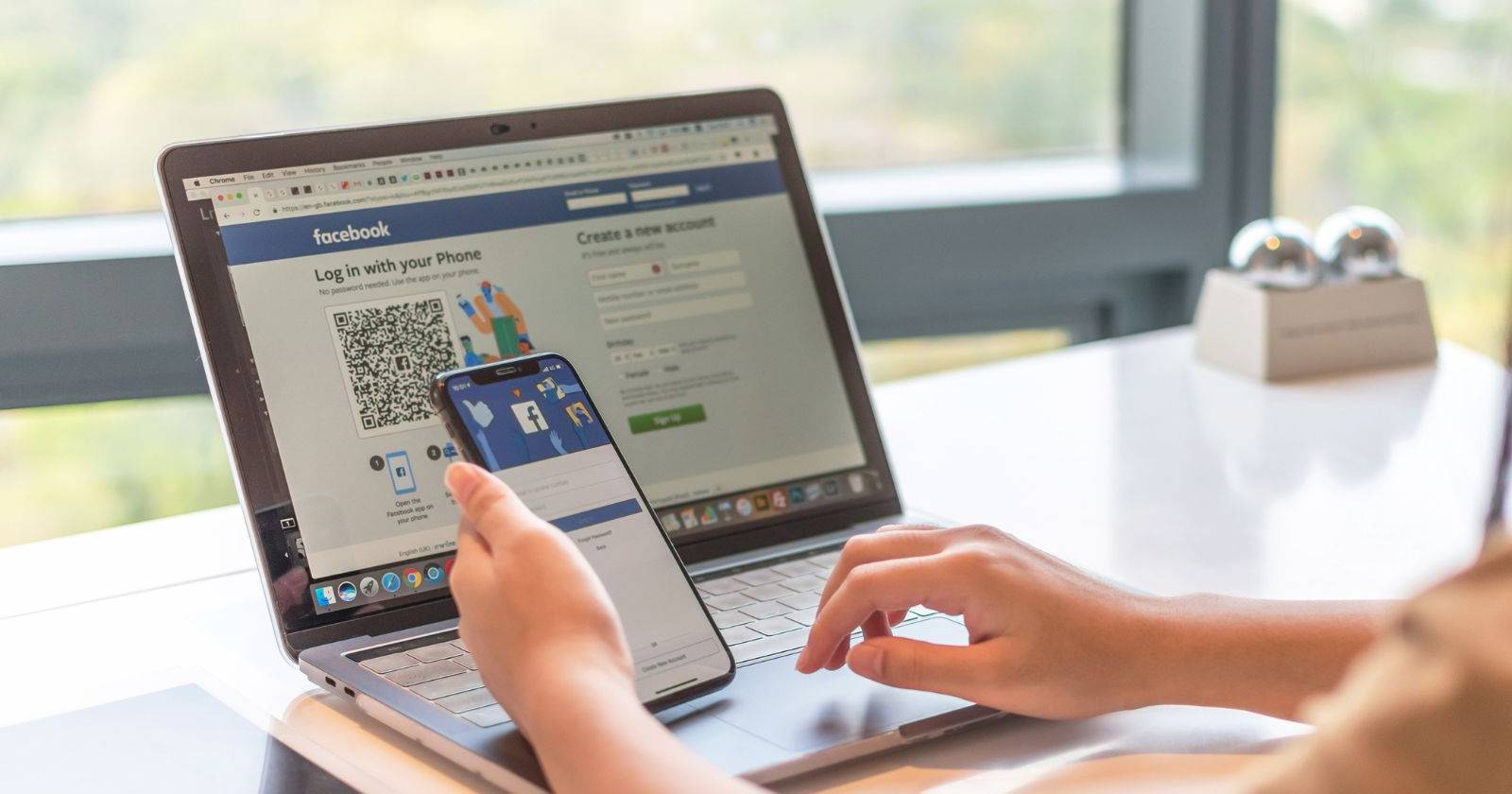 человек использует Facebook на телефоне перед ноутбуком