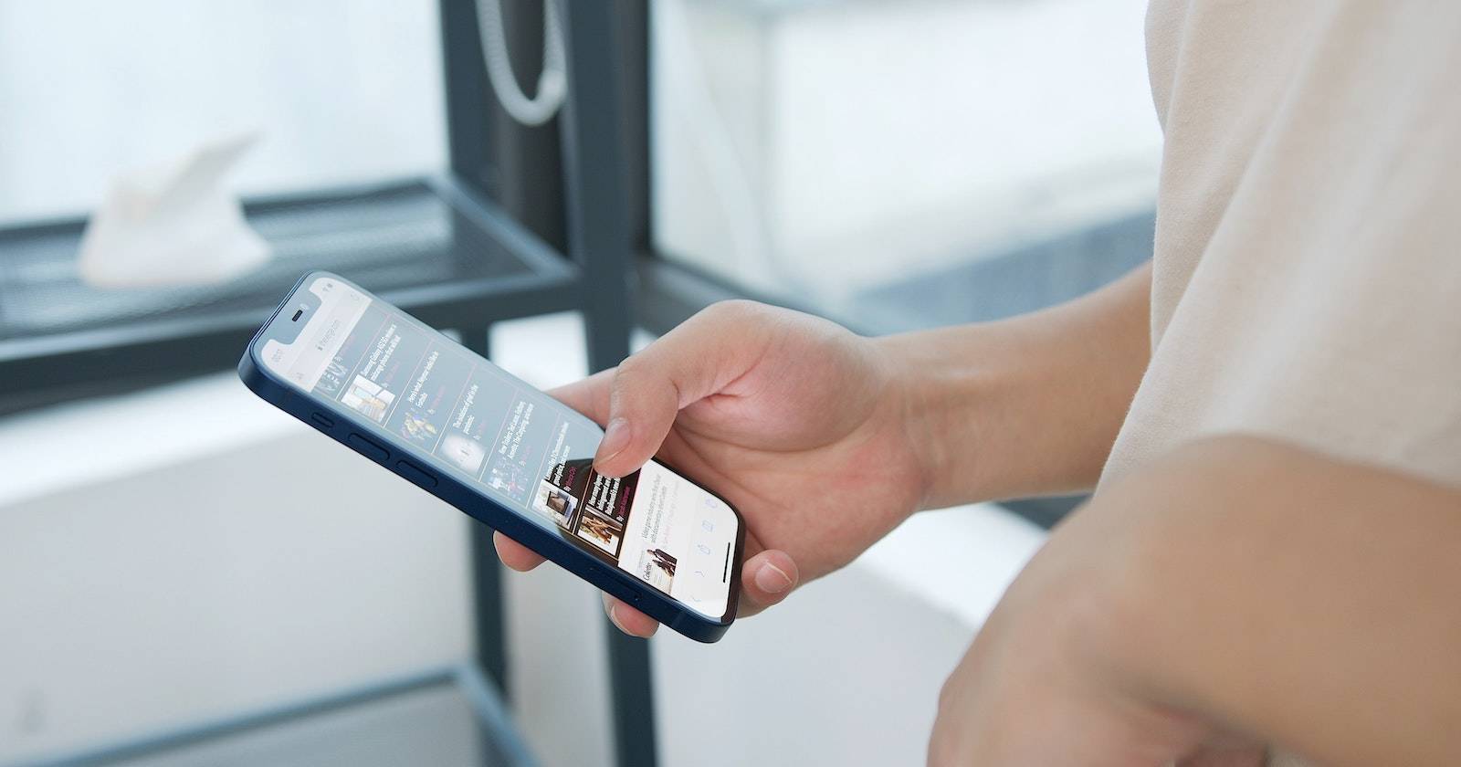 Рука держит iPhone с открытым экраном и приложением Feedback Assistant