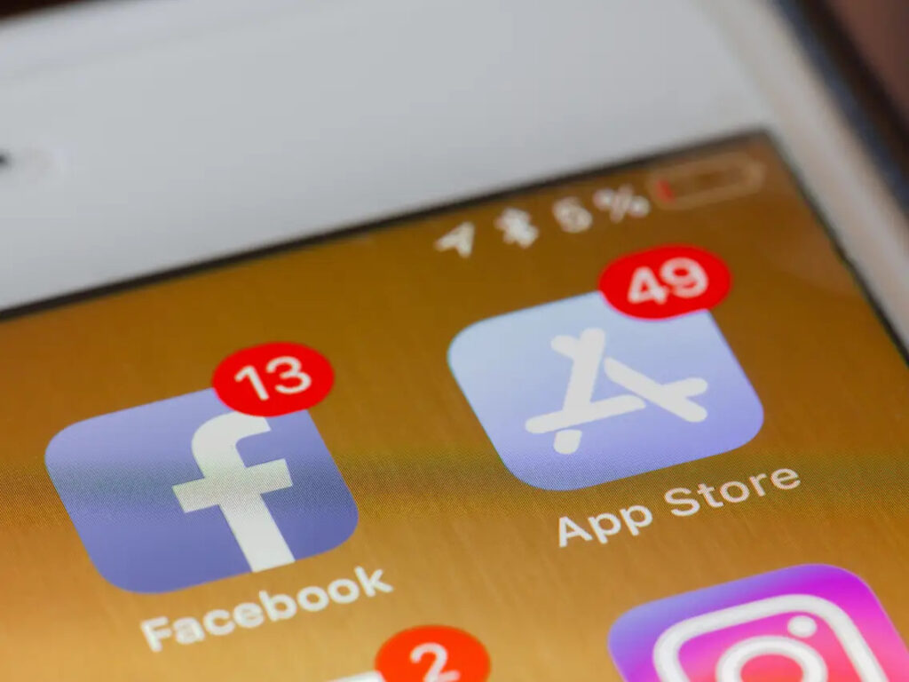 Mãos segurando um iPhone com tela de configurações de notificações