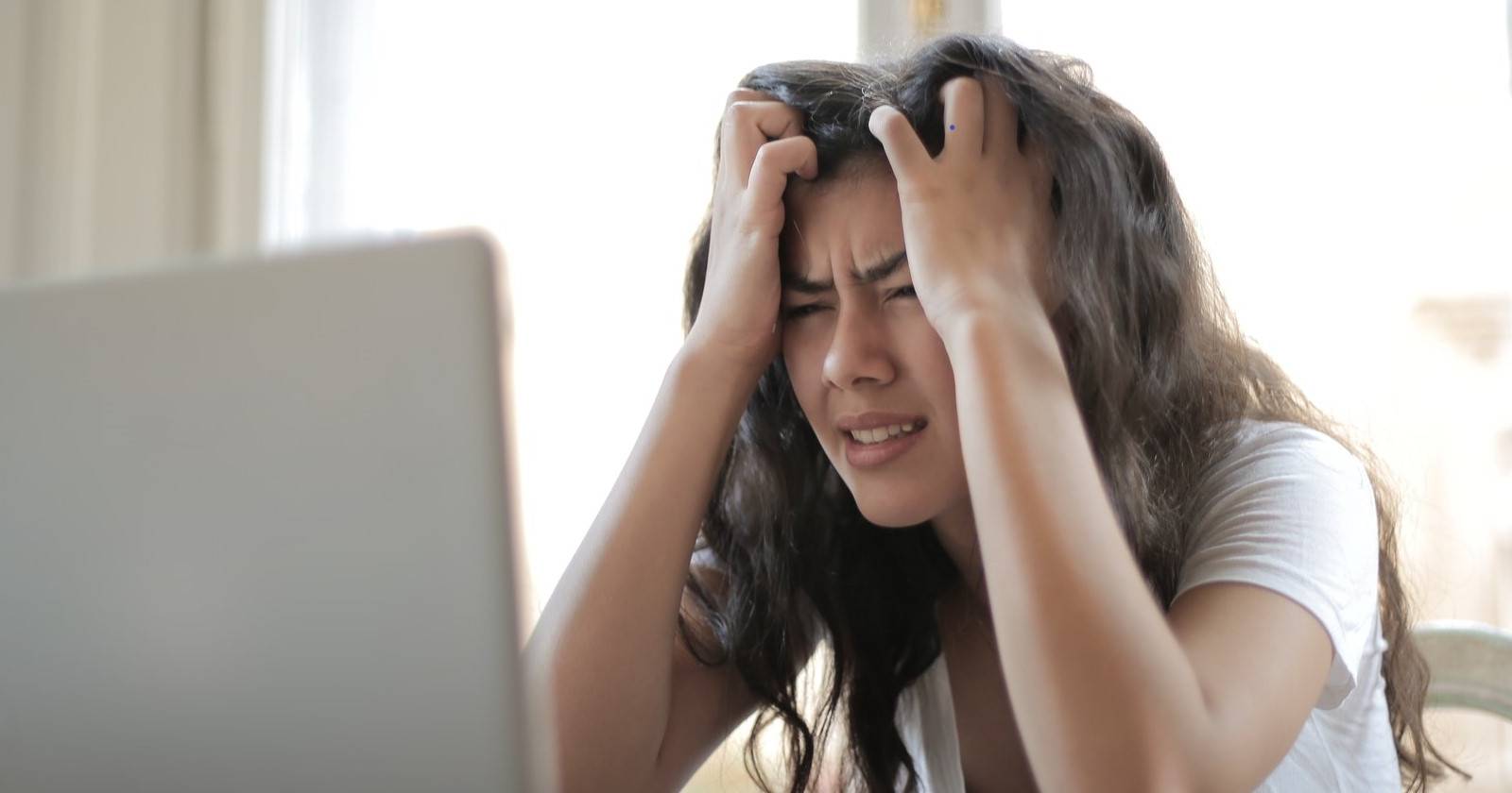 Раздражённая женщина смотрит на экран ноутбука