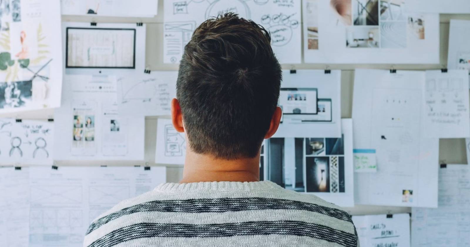 Человек смотрит на доску объявлений с множеством прикреплённых бумажек