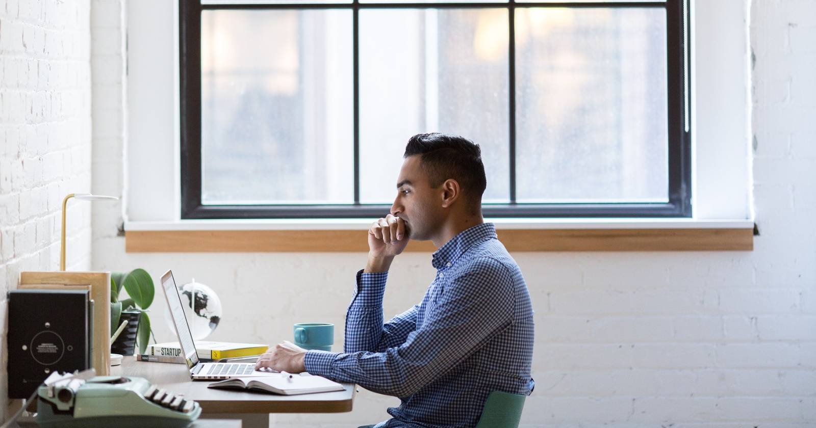 Мужчина работает за ноутбуком у окна