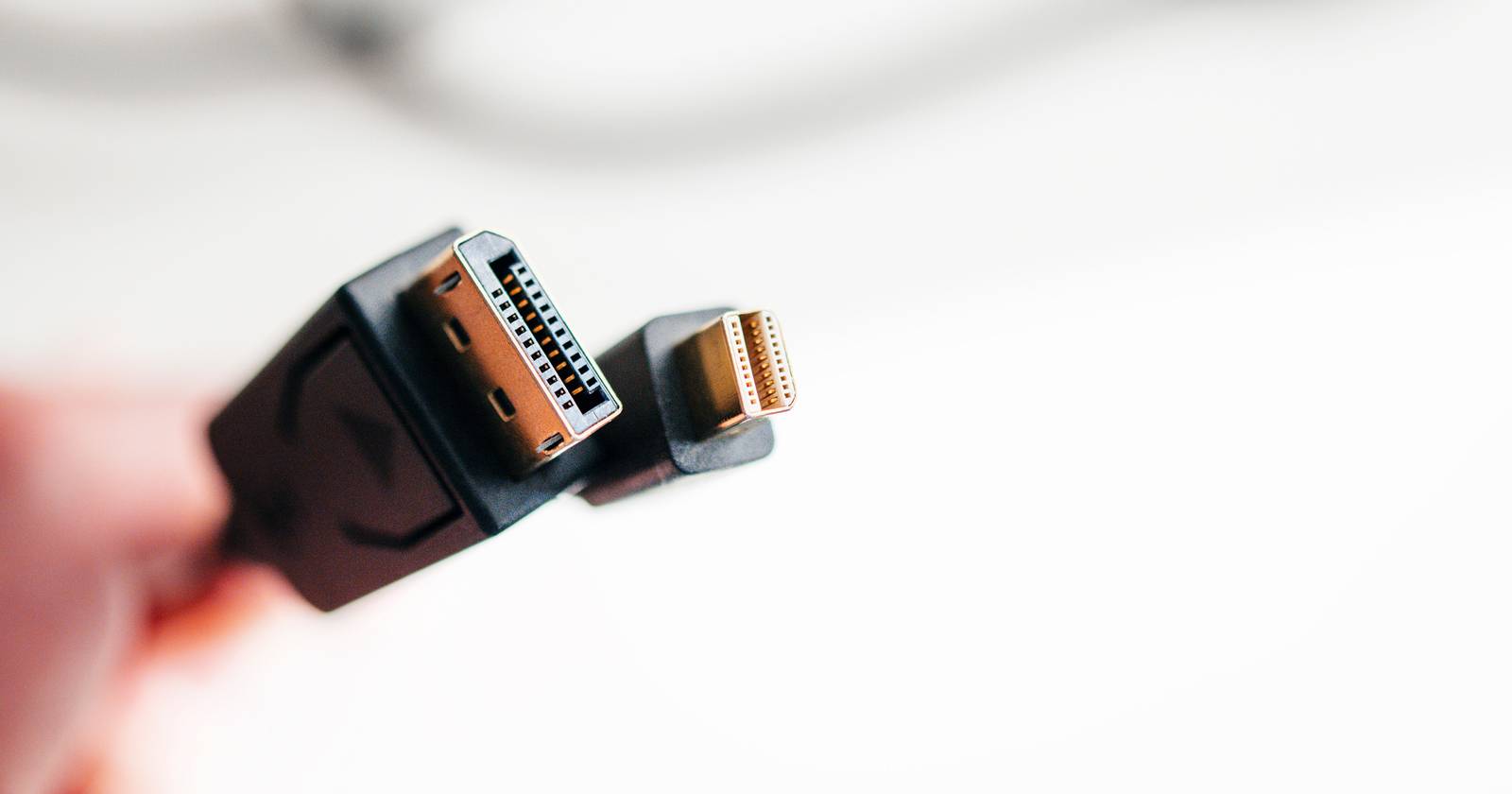 Человек держит кабель DisplayPort рядом с монитором