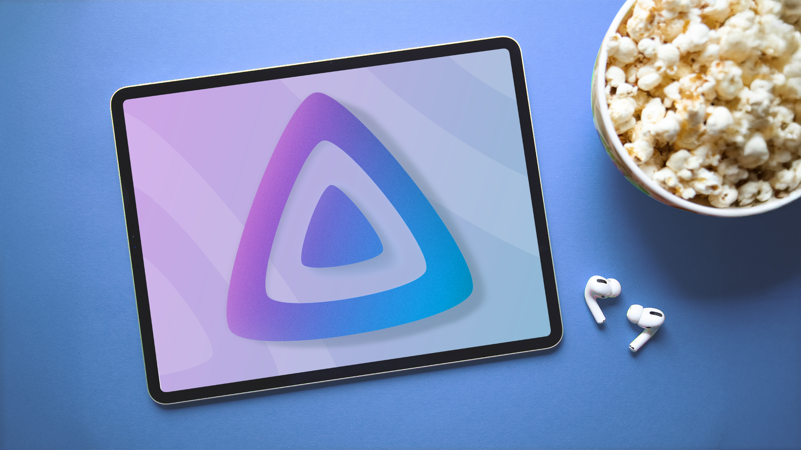 Планшет с логотипом Jellyfin рядом с миской попкорна и беспроводными наушниками.