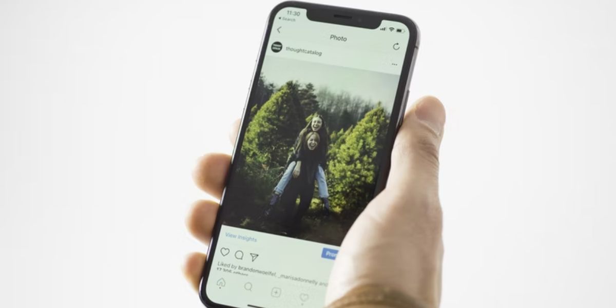 Человек держит iPhone с открытым постом Instagram