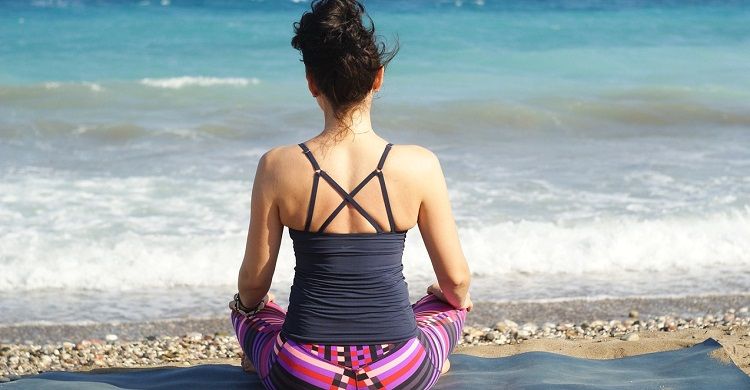 Изображение женщины, занимающейся йогой рядом с водой