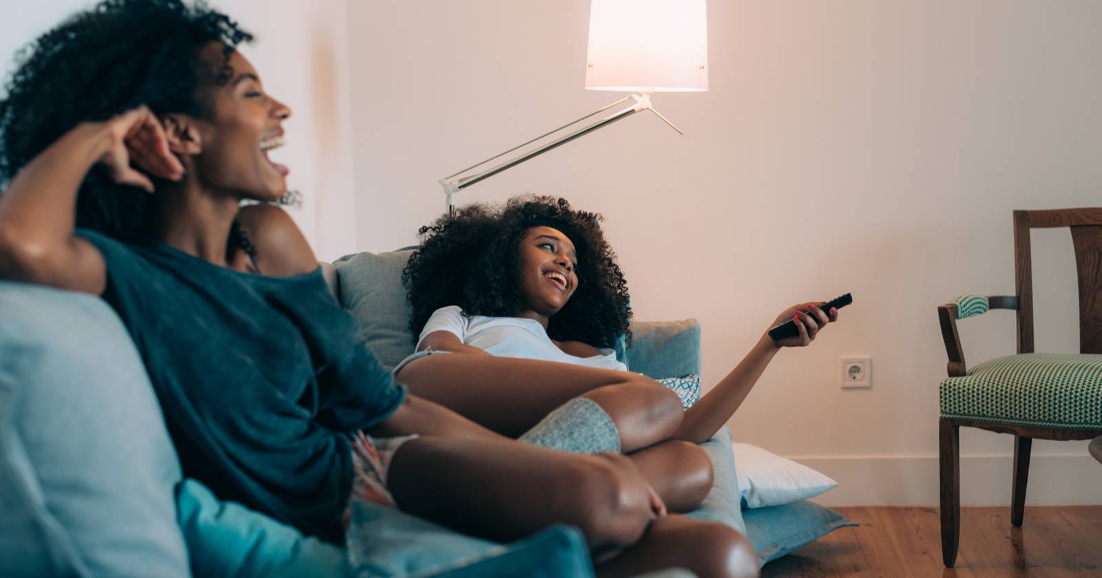 Две женщины сидят на диване и смотрят телевизор вместе