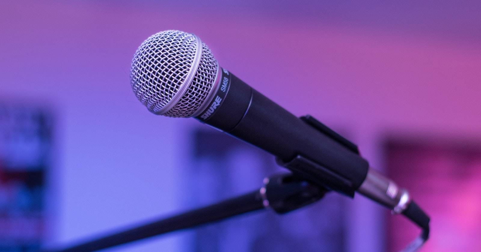 Крупный план вокального микрофона Shure SM58 на фиолетово-голубом фоне