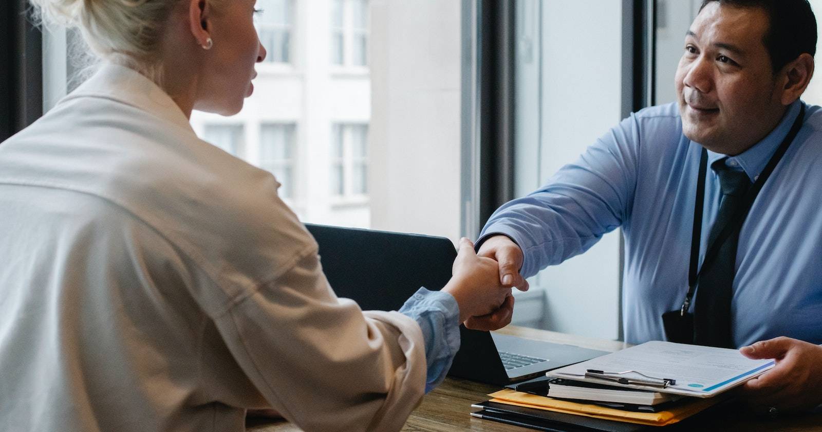 Два человека пожимают руки в офисе