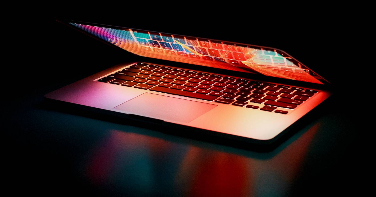 Полуоткрытый MacBook на столе с яркими цветовыми акцентами