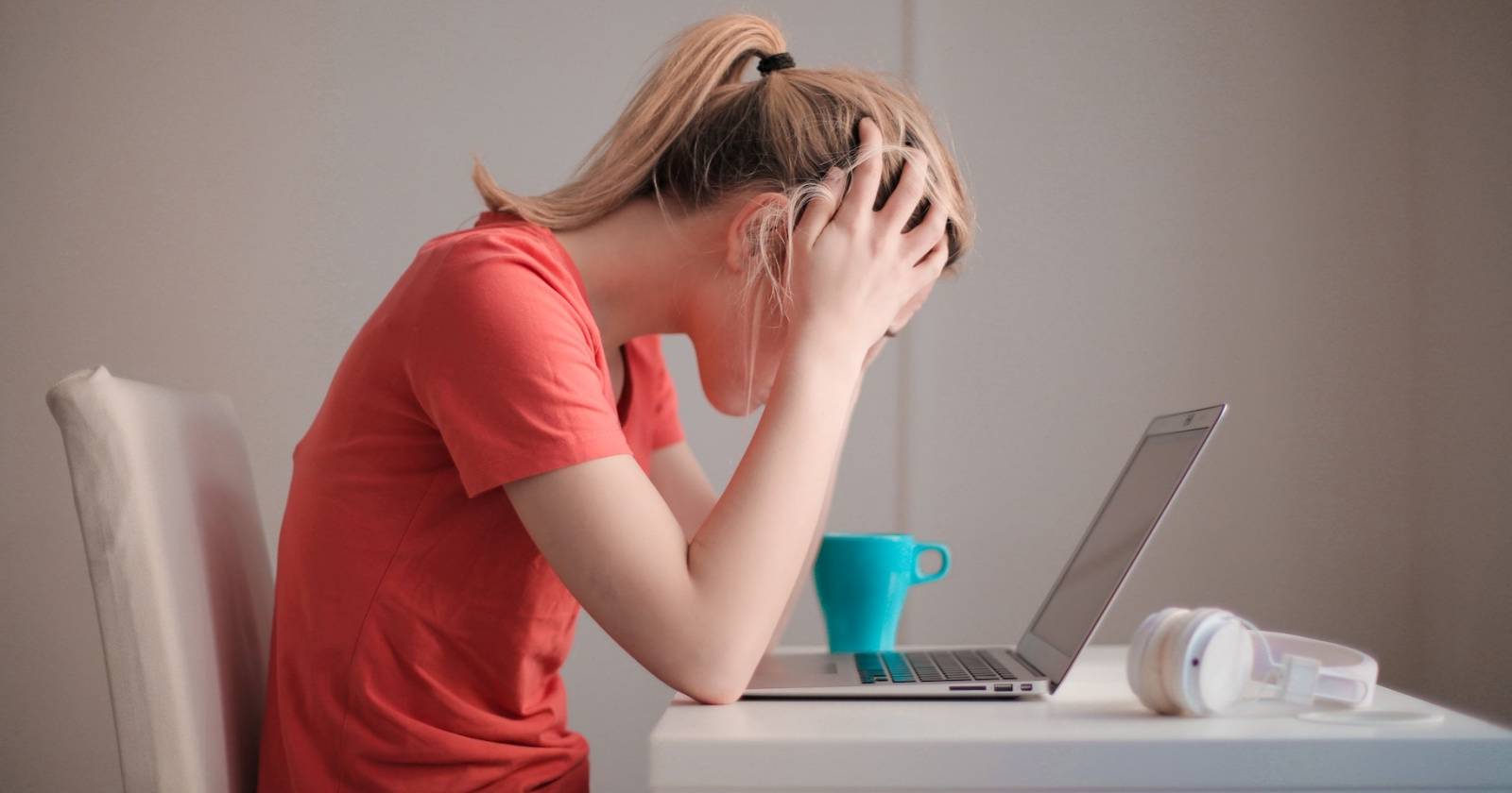Девушка с хвостиком держит голову в разочаровании перед ноутбуком