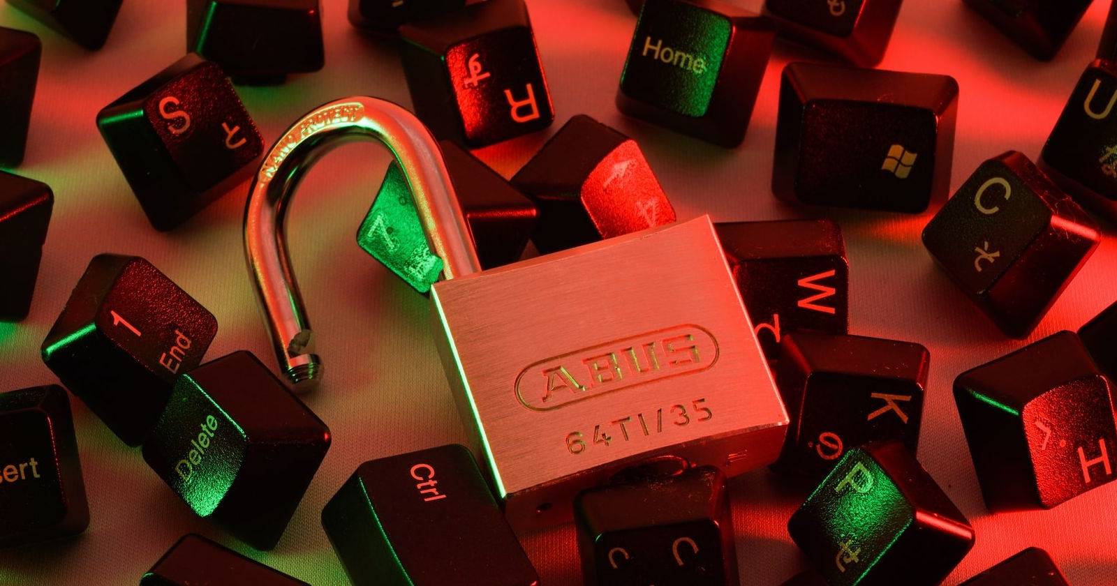 Разблокированный замок на разбросанных клавишах компьютера.