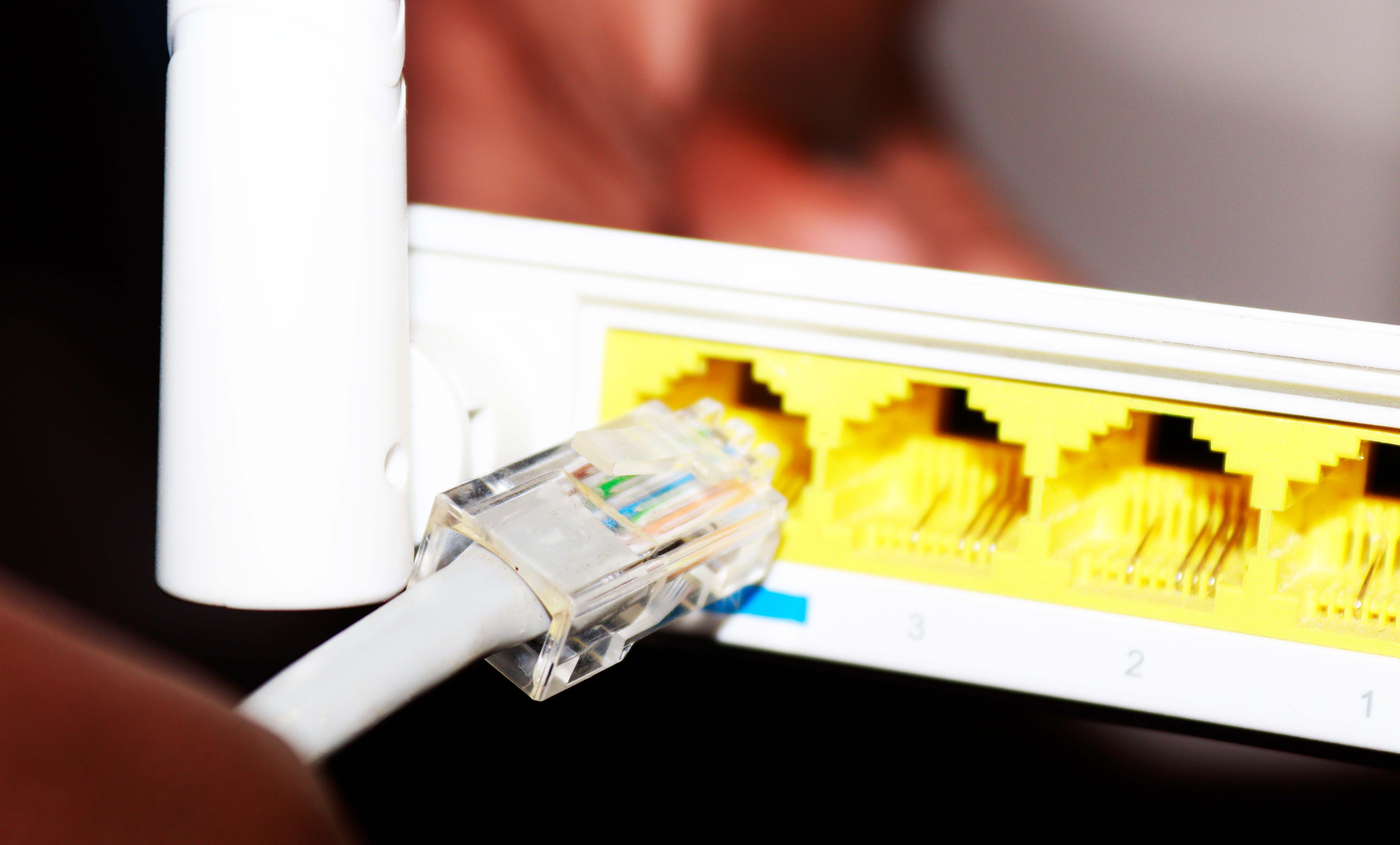 Белый Ethernet‑кабель вставляется в роутер