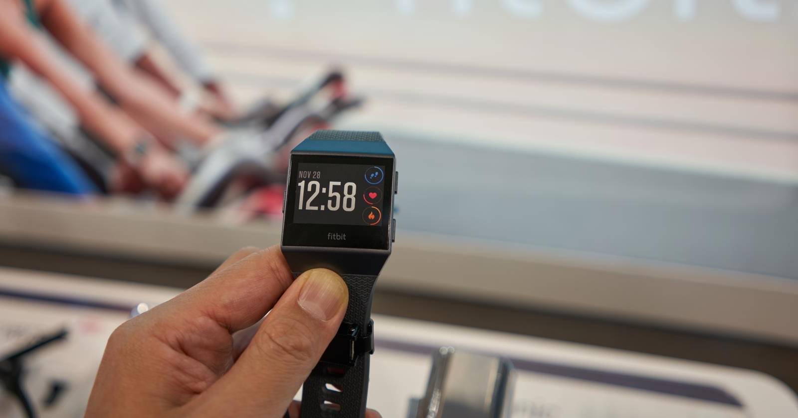 Фитнес-трекер Fitbit на запястье, экран показывает время