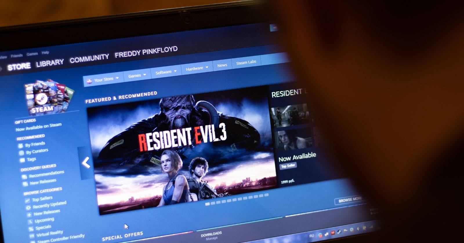 человек смотрит на экран ноутбука со страницей магазина Steam