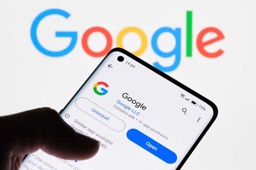 Приложение Google показано на экране смартфона, логотип Google на фоне