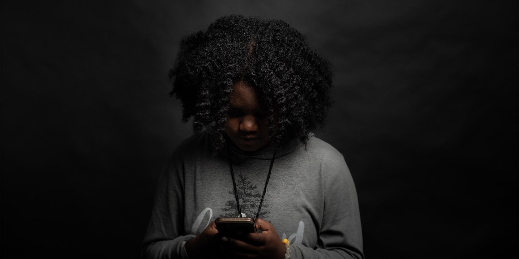 Girl intensely using mobile phone in a dark room.