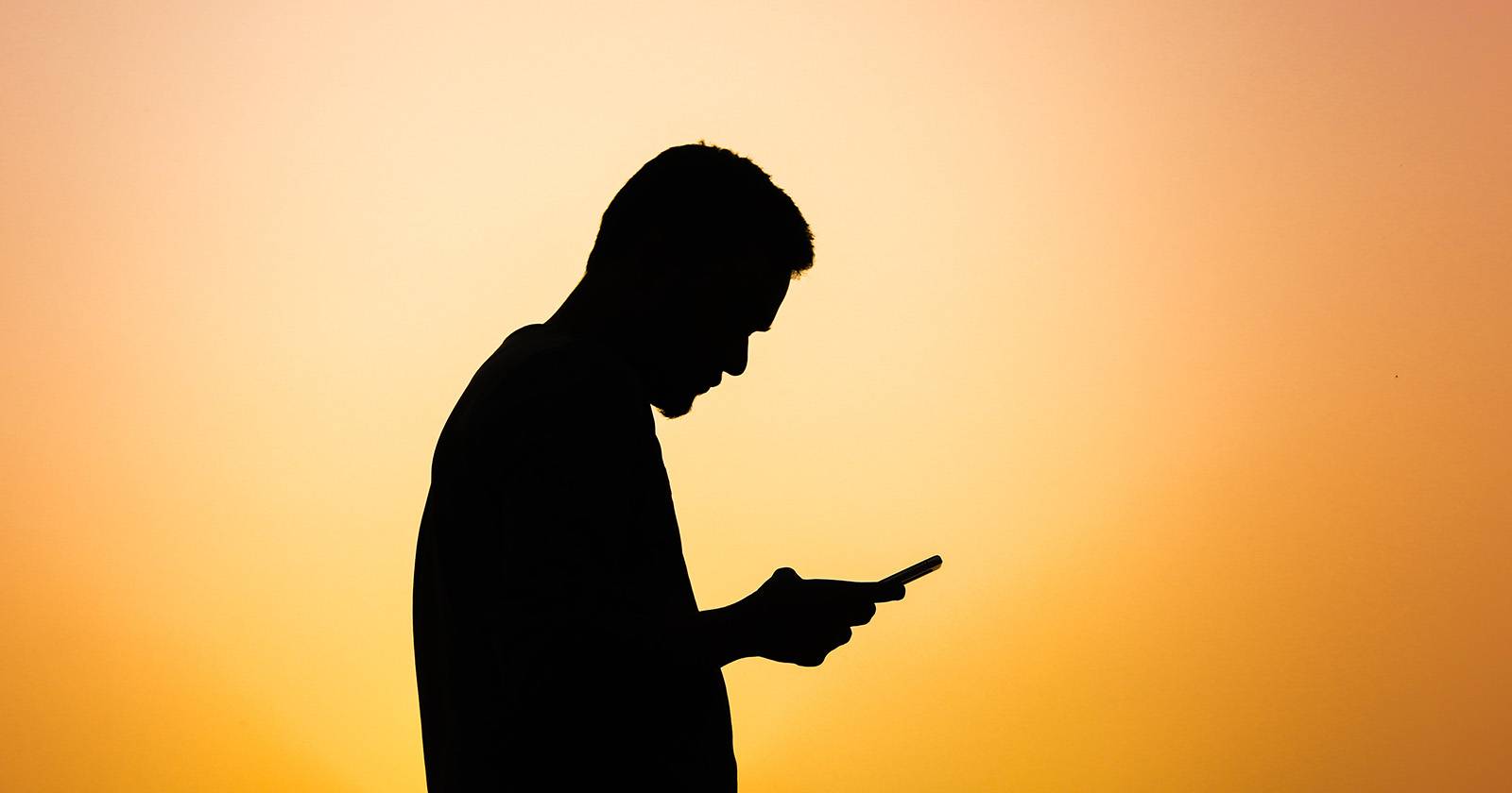 Человек с телефоном, силуэт на фоне солнца