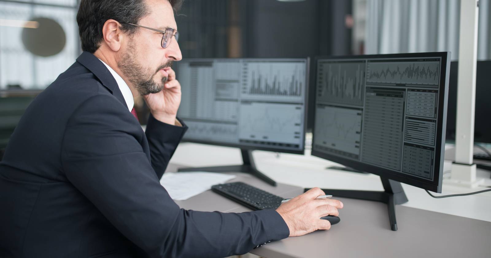 Мужчина в тёмном костюме сидит перед компьютером