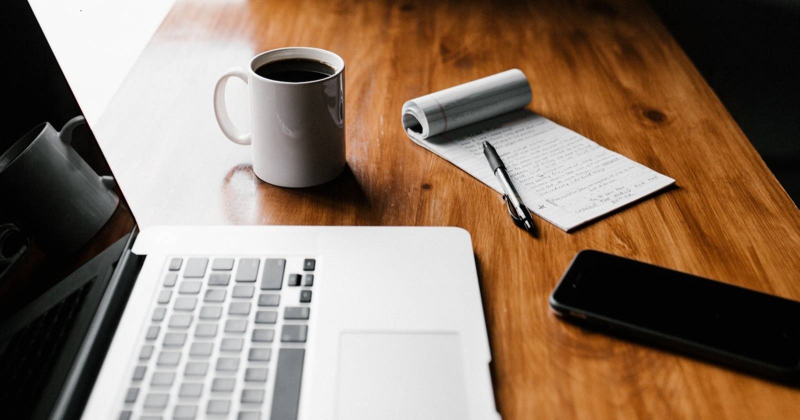 Ноутбук, телефон и чашка кофе на деревянном столе