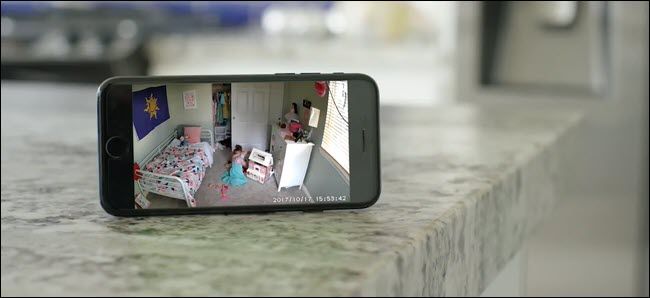 Экран iPhone показывает трансляцию с Wyze Cam: ребёнок играет в комнате