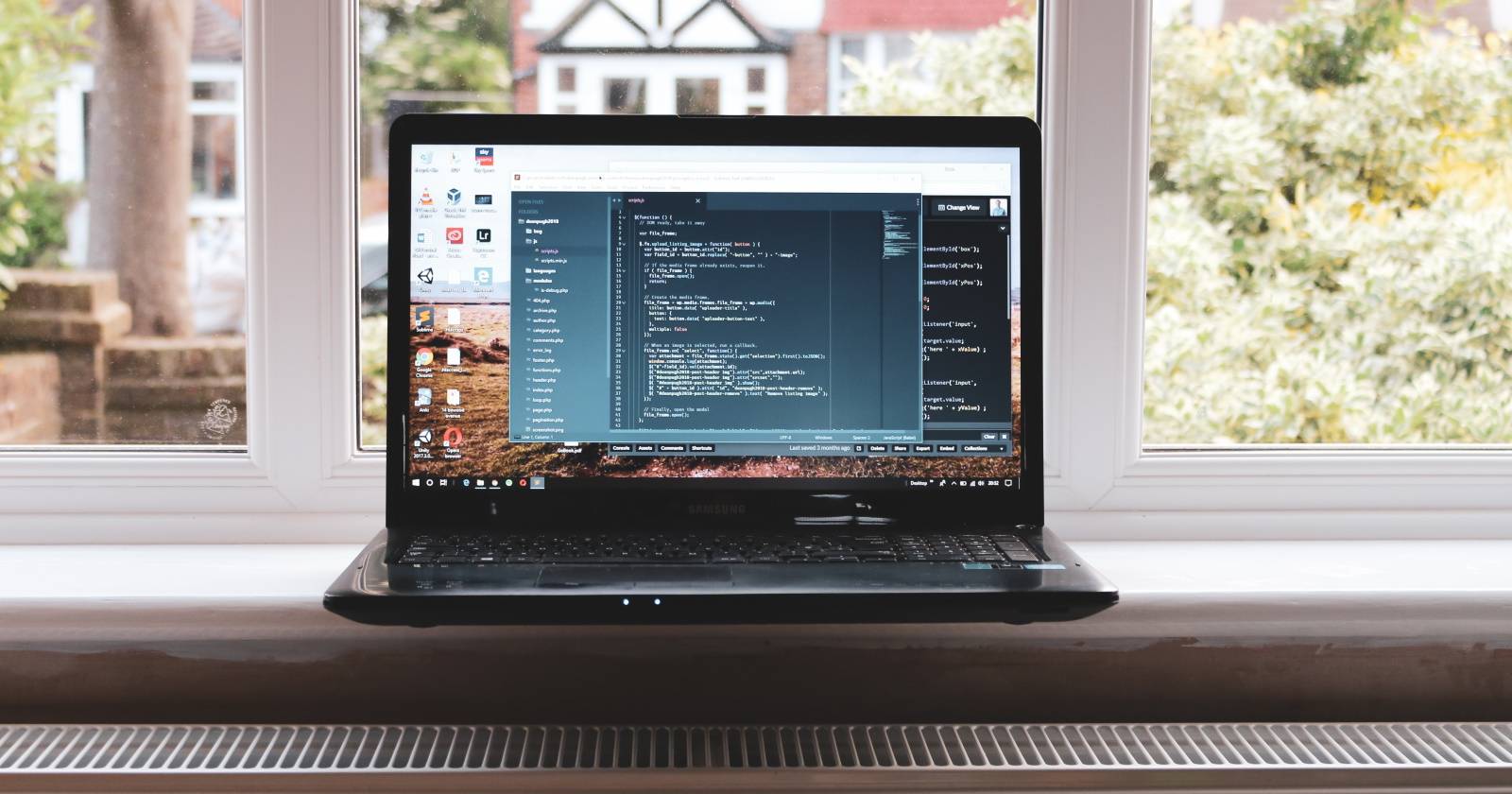 Ноутбук у окна с кодом на экране