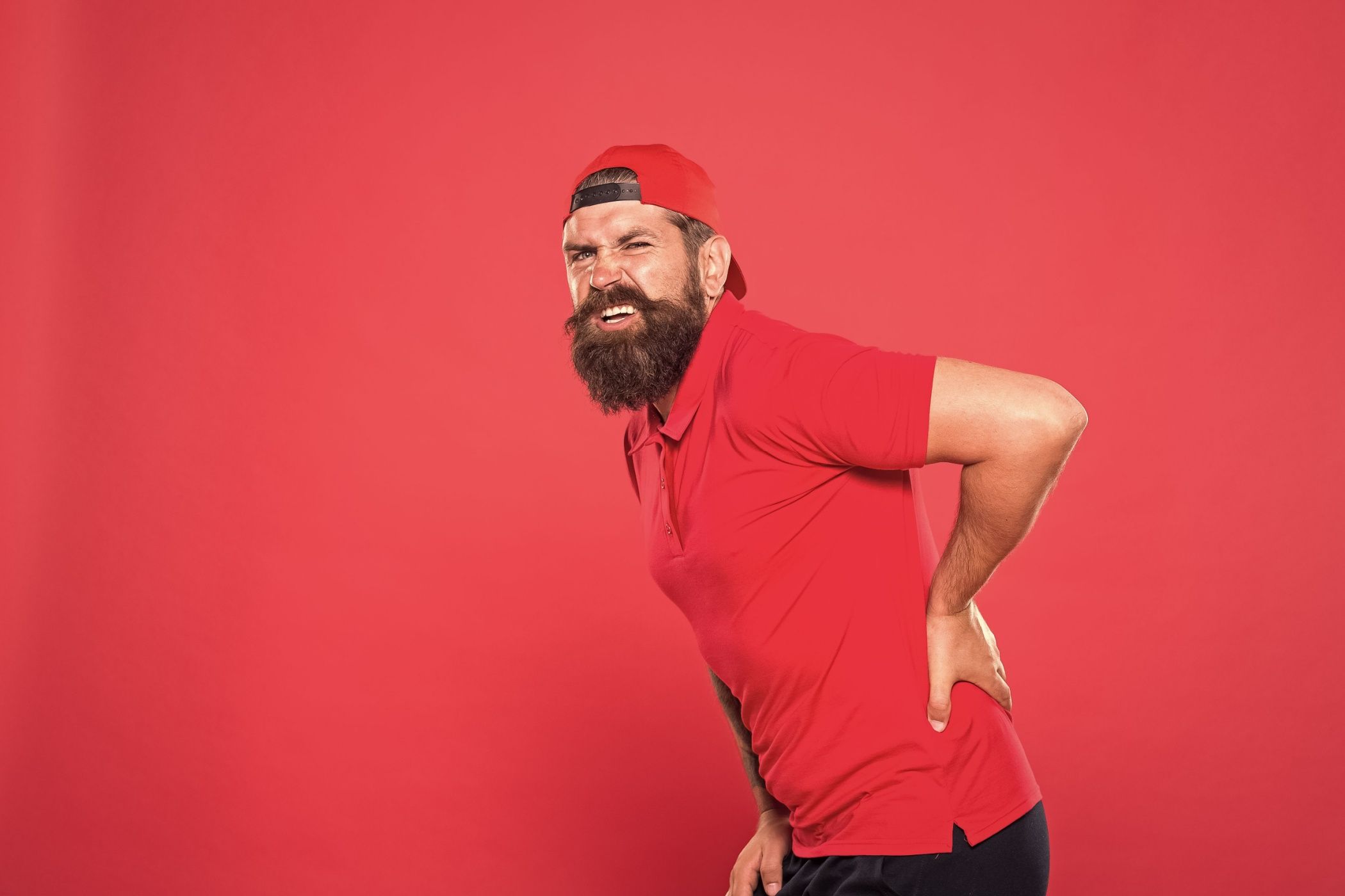 Мужчина трогает нижнюю часть спины от боли