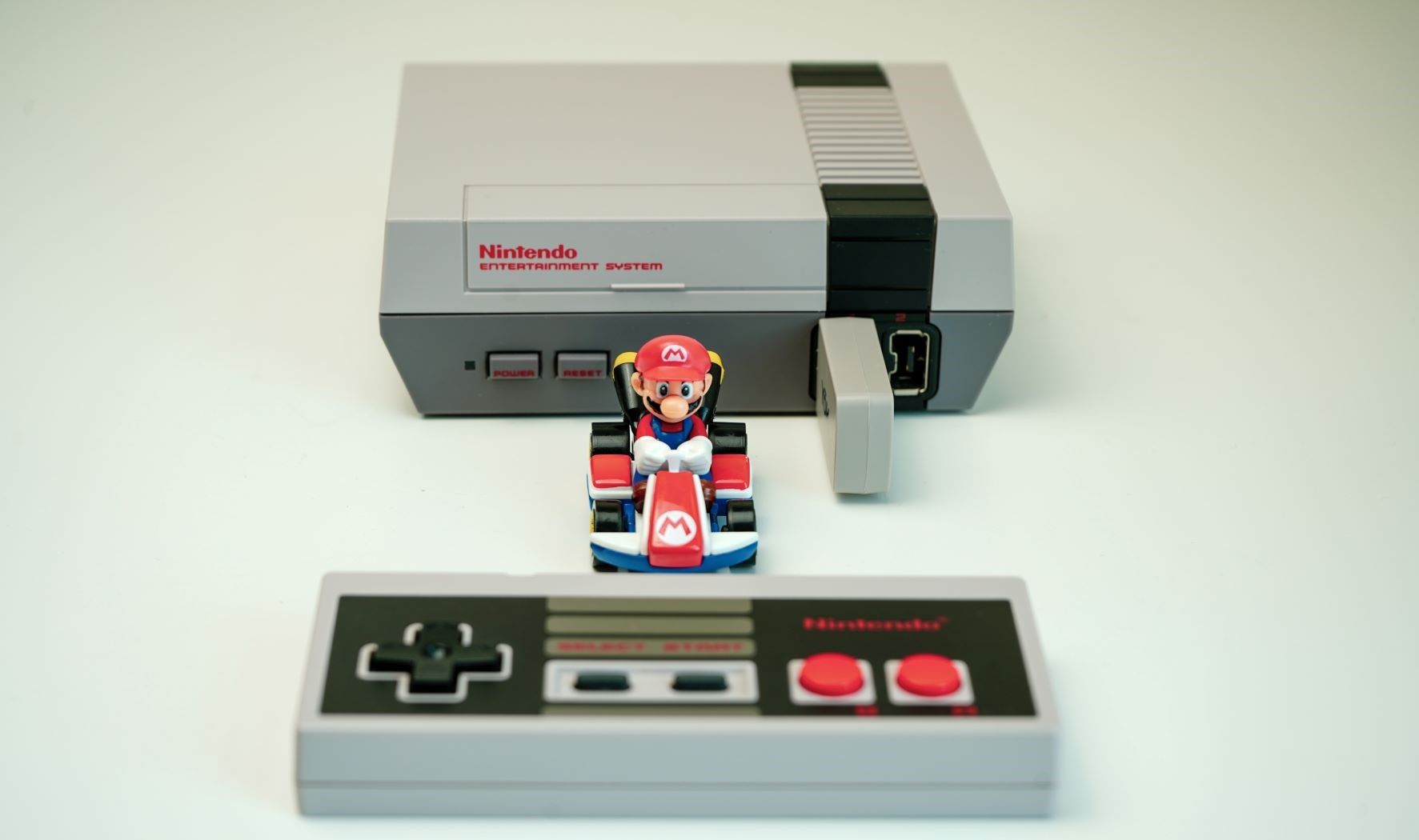 Классическая NES рядом с фигуркой Mario Kart