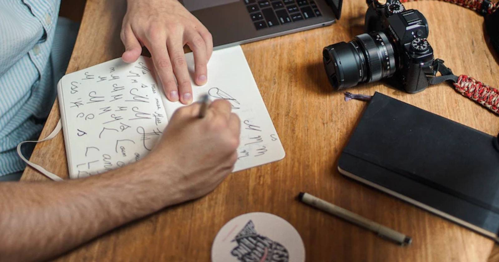 человек рисует на бумаге рядом с фотоаппаратом