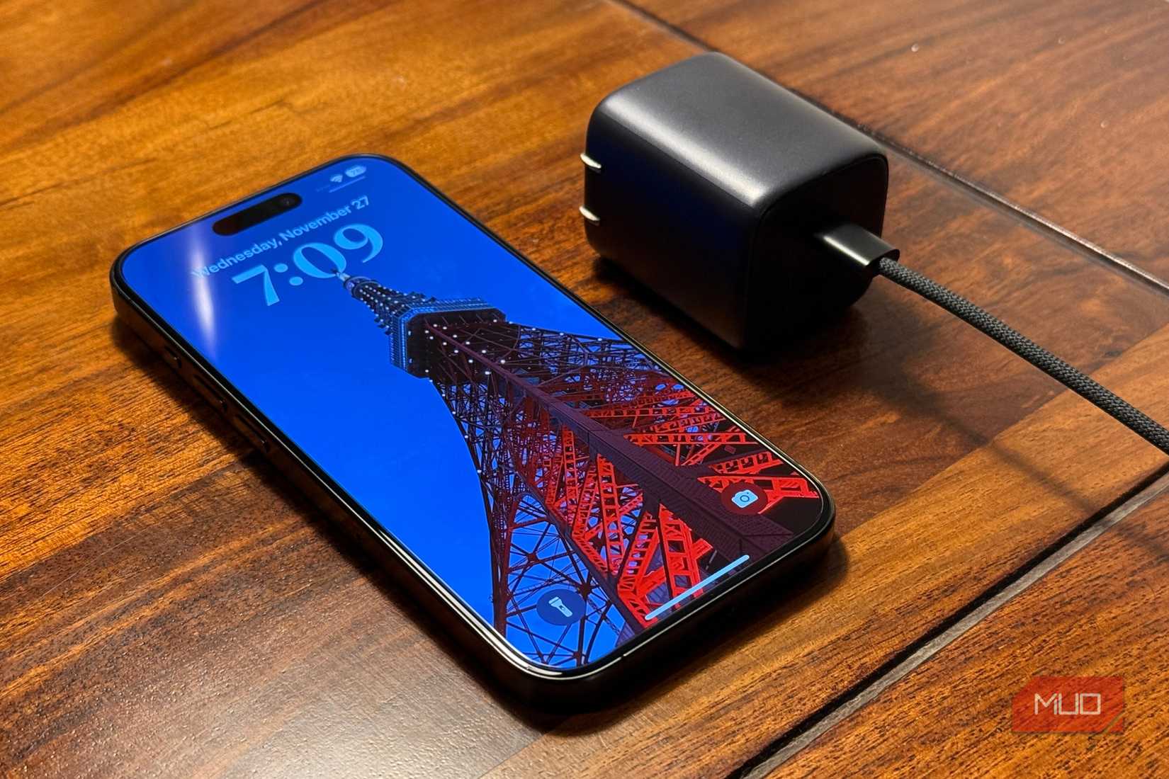 iPhone рядом с сетевым адаптером на деревянном столе