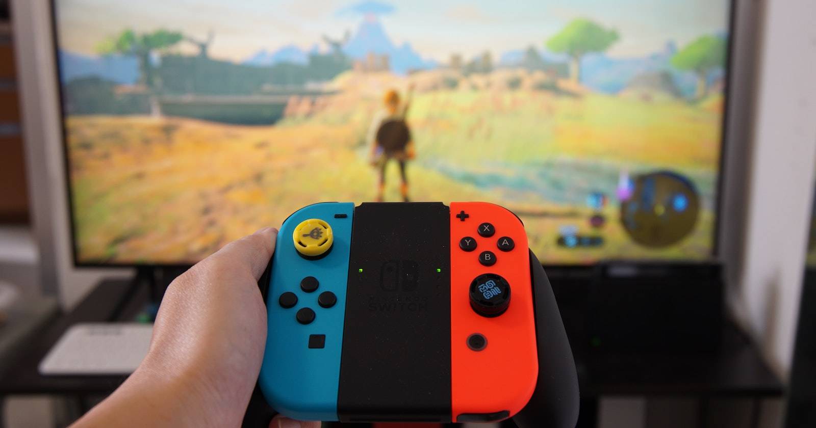 Человек держит Nintendo Switch с джойконами