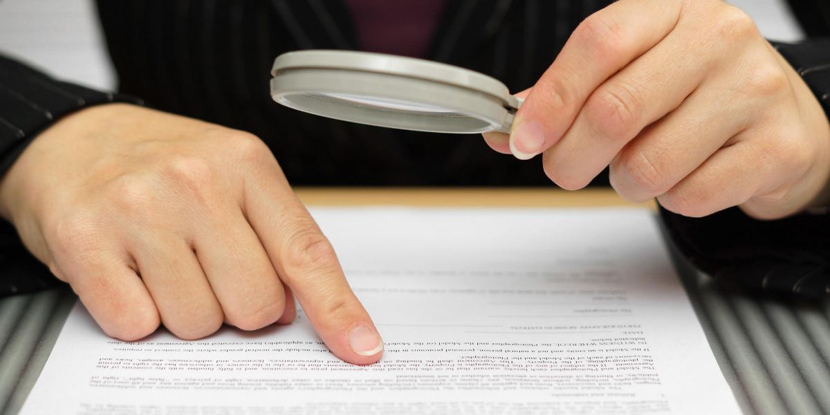 Человек с увеличительным стеклом проверяет документ