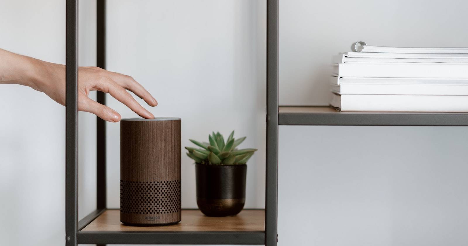 Рука прикасается к устройству Amazon Echo