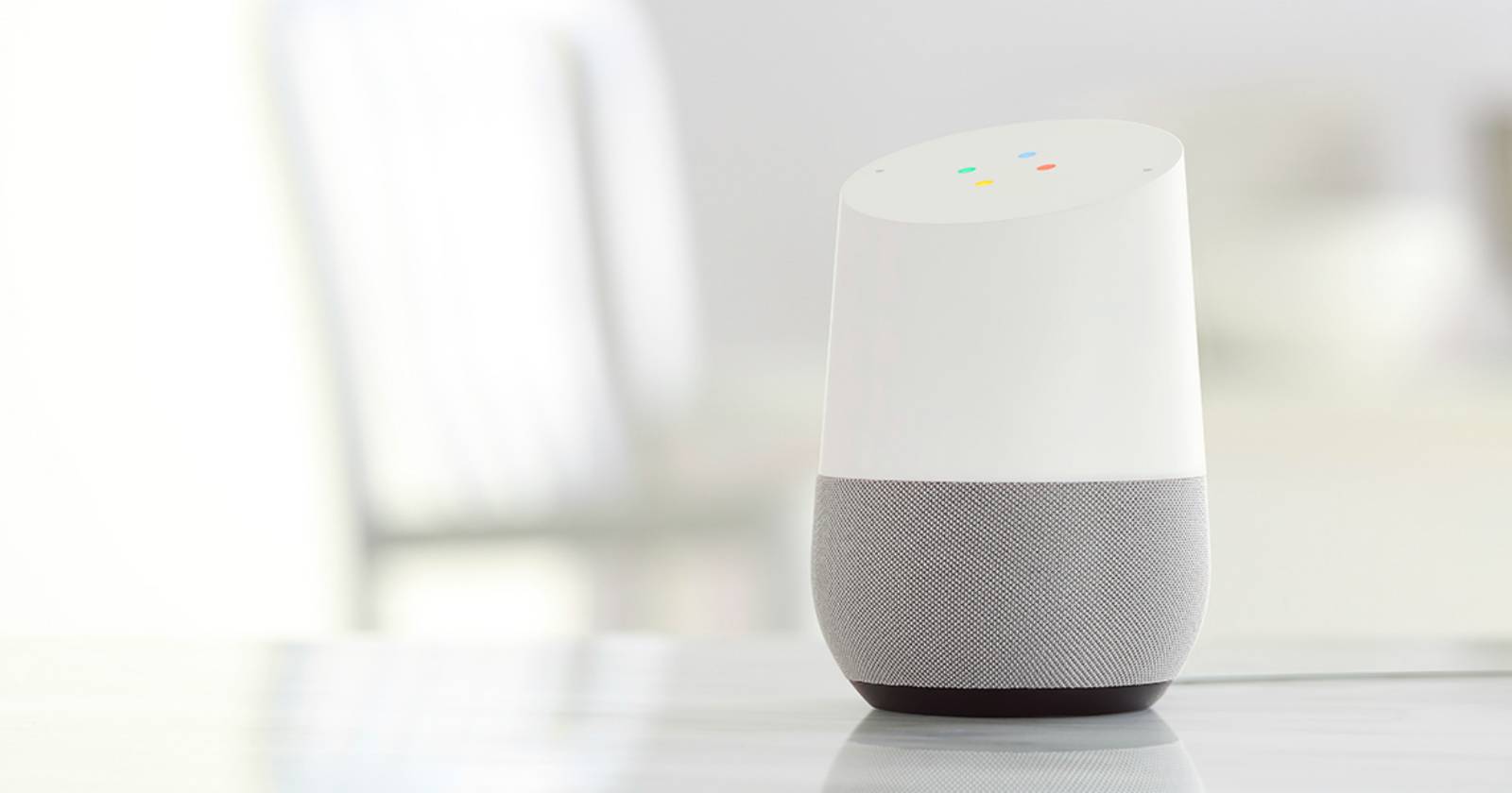 Google Home на белом столе рядом с телефоном и аксессуарами