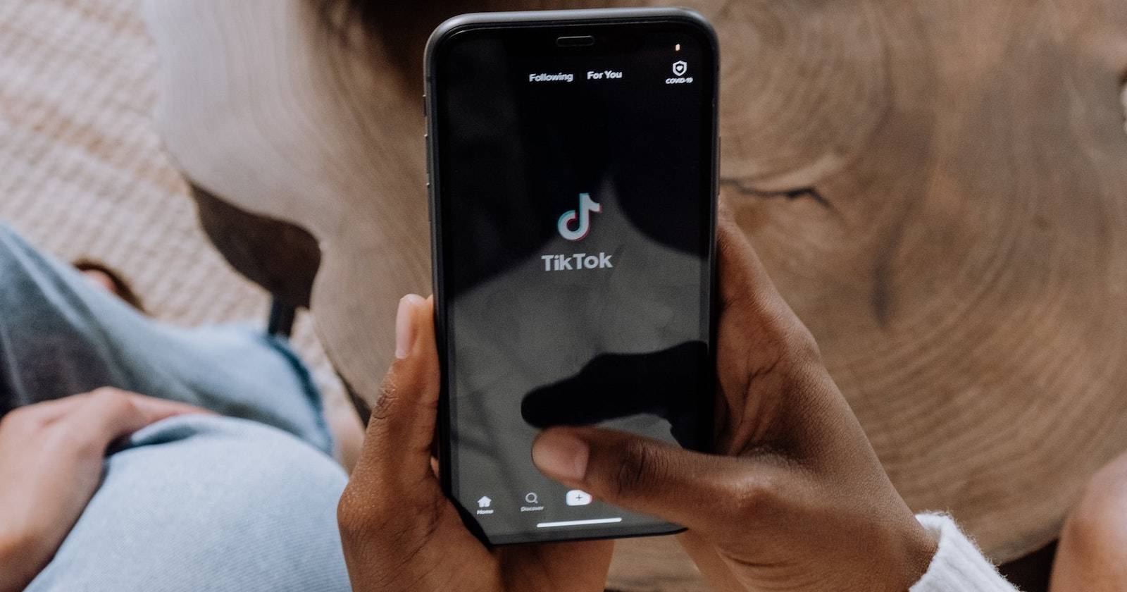 Руки держат смартфон с логотипом TikTok на экране