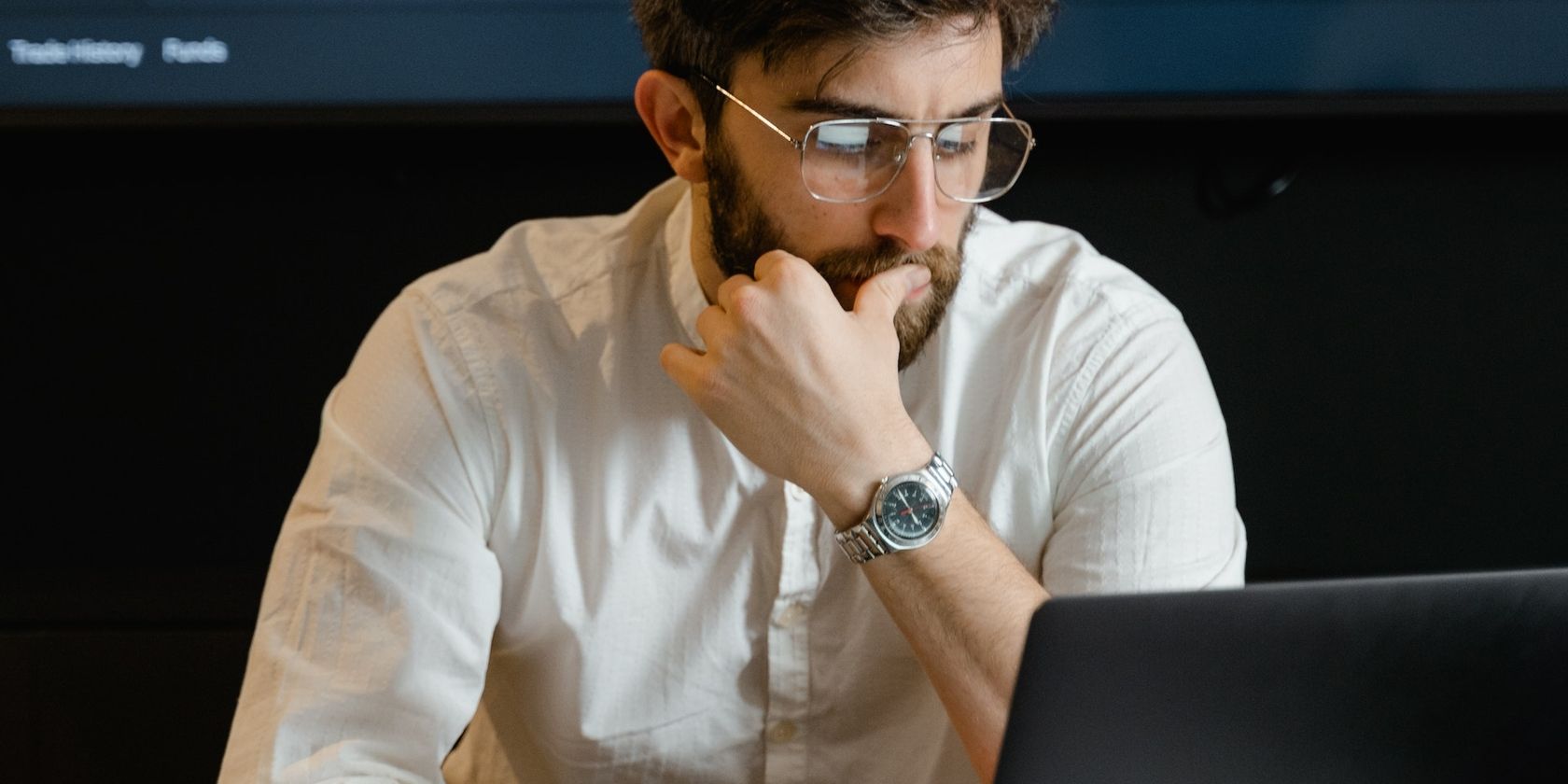 man uses laptop with thoughtful expression