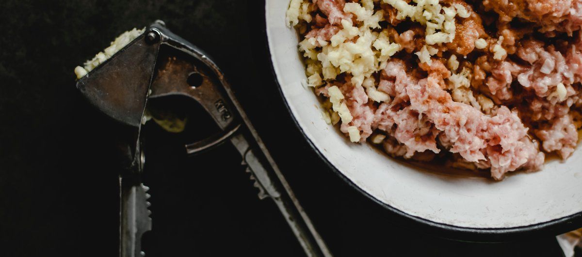 Использованная чесночница рядом с миской сырого продукта