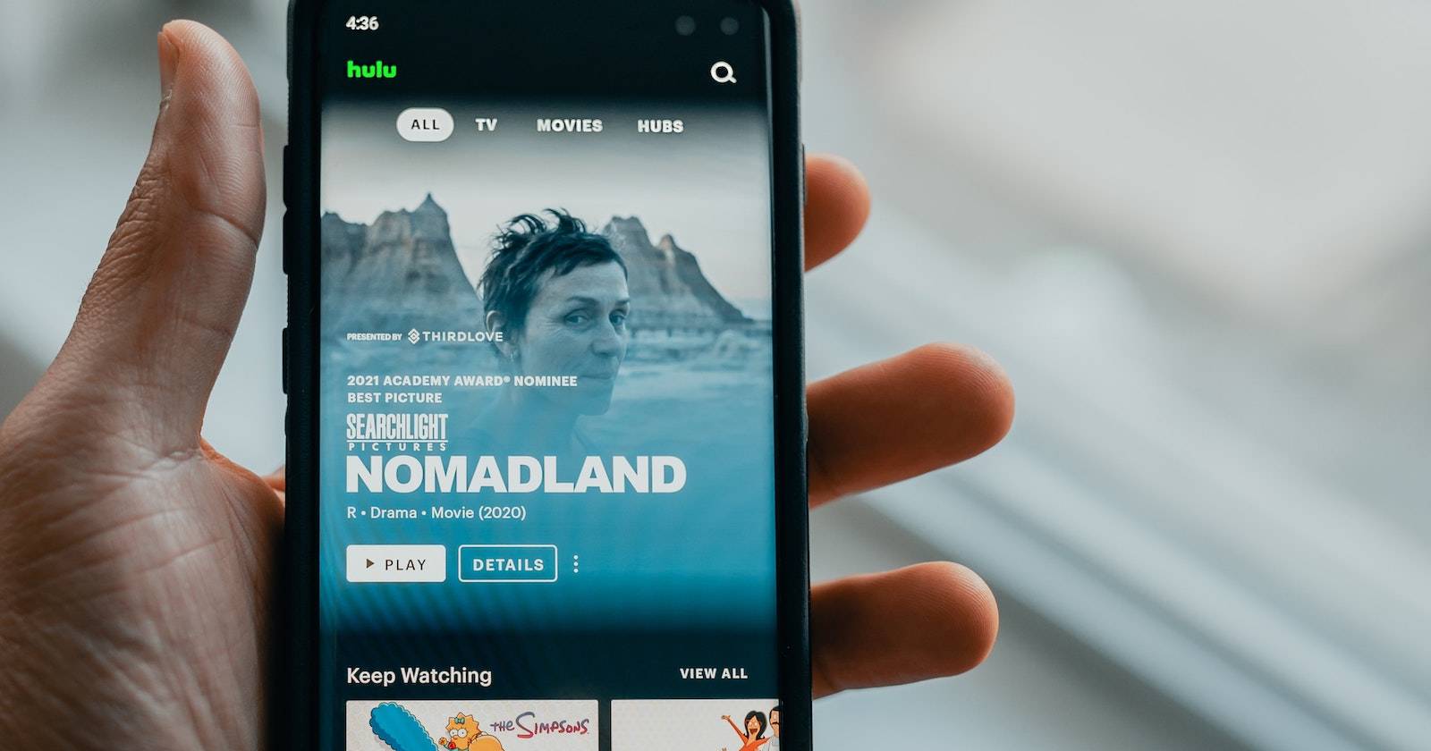 Человек держит телефон с приложением Hulu на экране