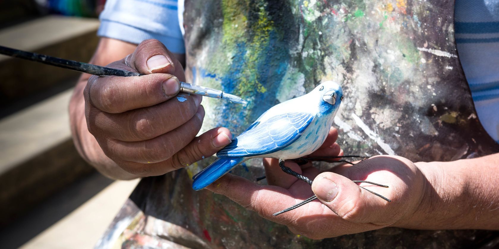 человек расписывает фигуру птицы красками