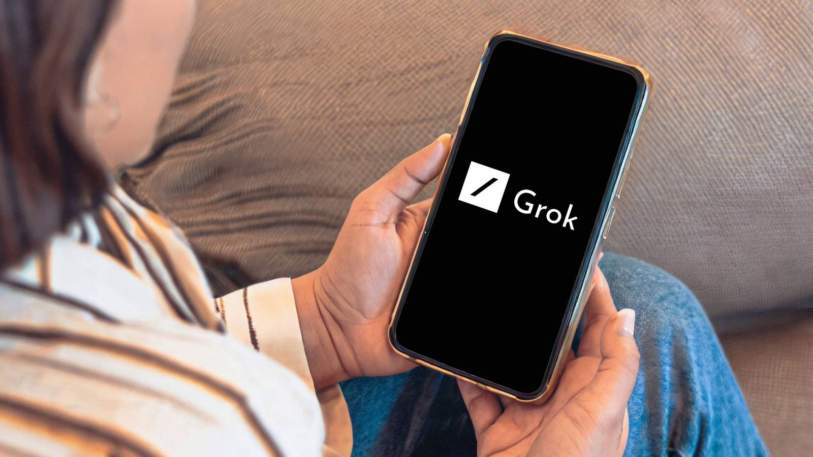 человек смотрит на смартфон с логотипом Grok AI