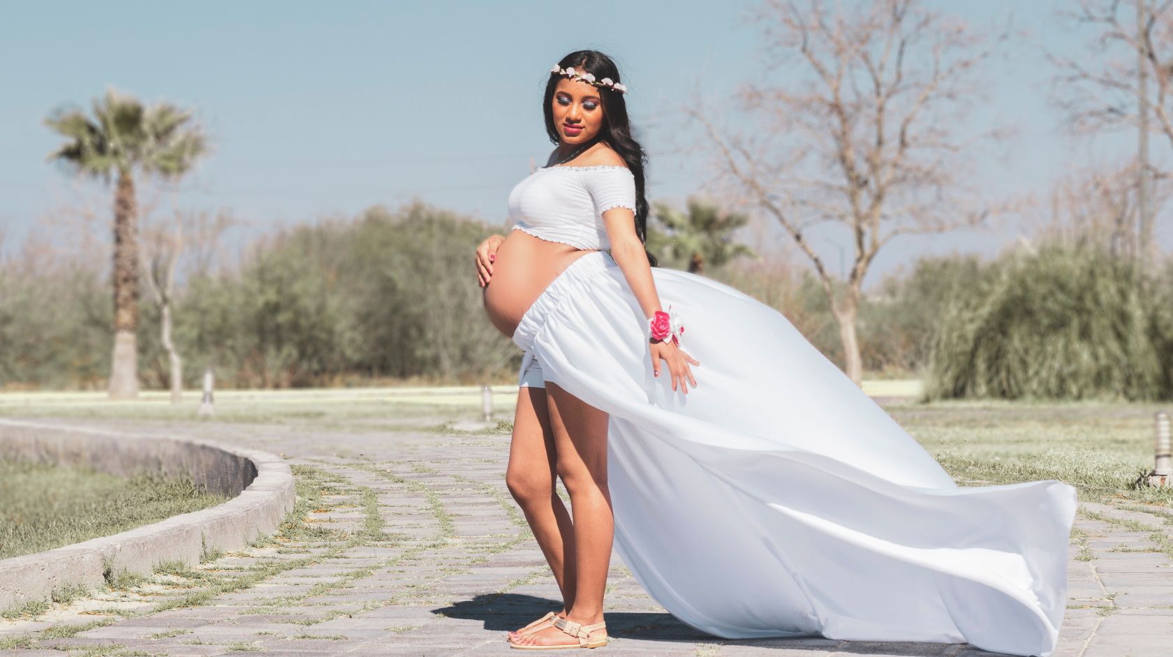 Беременная женщина в белом платье, платье развевается на ветру