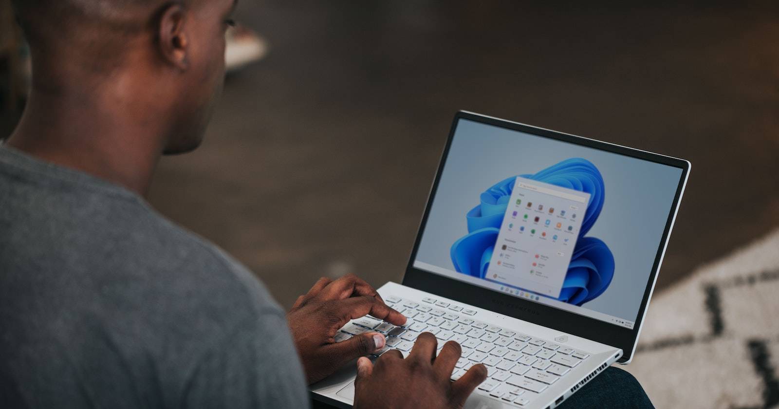 Мужчина за ноутбуком, использующий Windows 11 и увеличивающий изображение на экране