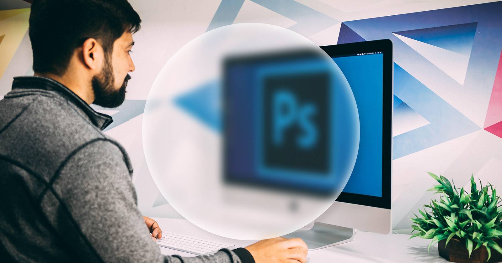 Человек сидит перед экраном Mac с логотипом Photoshop. Круглая форма со «стеклянным» эффектом сверху.
