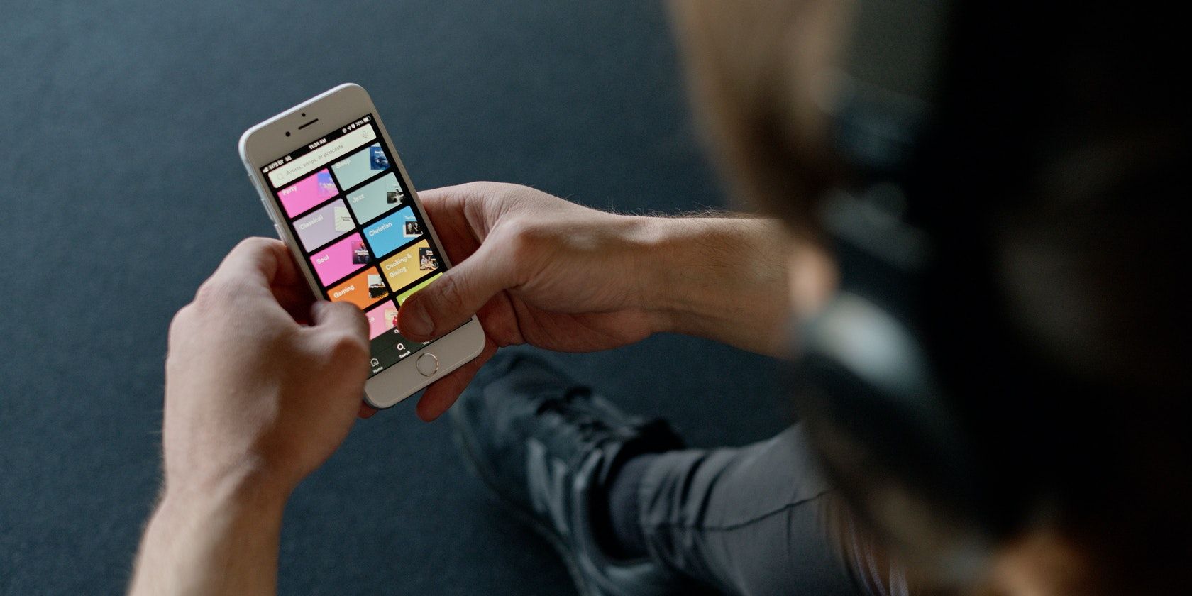 Человек держит телефон в наушниках