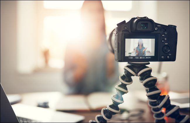 A camera on a tripod filming a woman speaking.