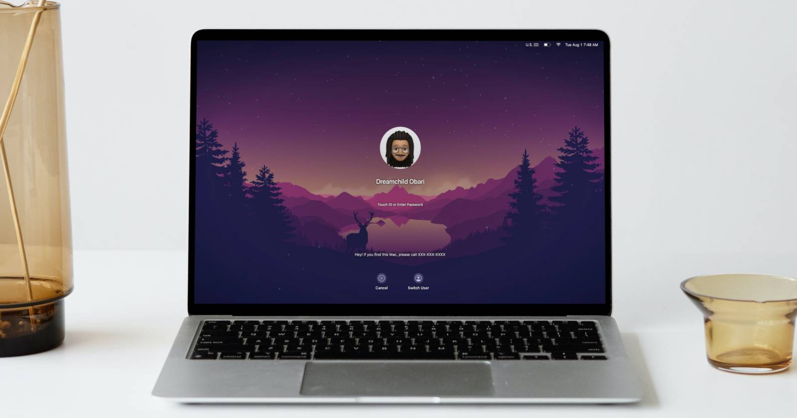 MacBook Air на белом столе, на экране блокировки показан Memoji