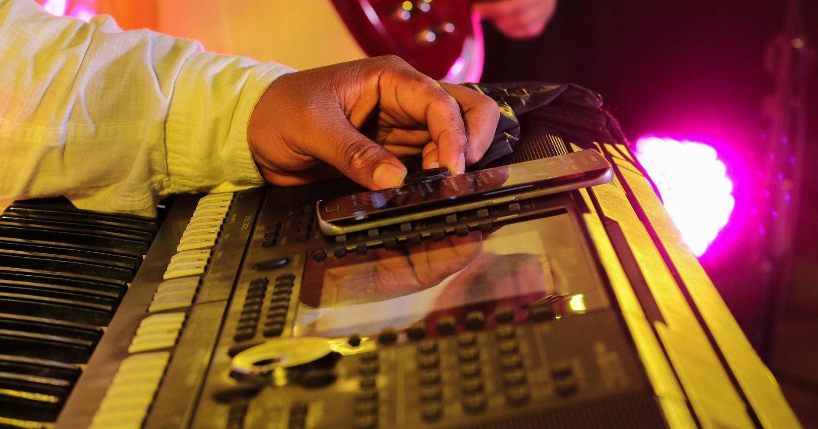 Produttore davanti a una tastiera MIDI con uno smartphone poggiato sopra