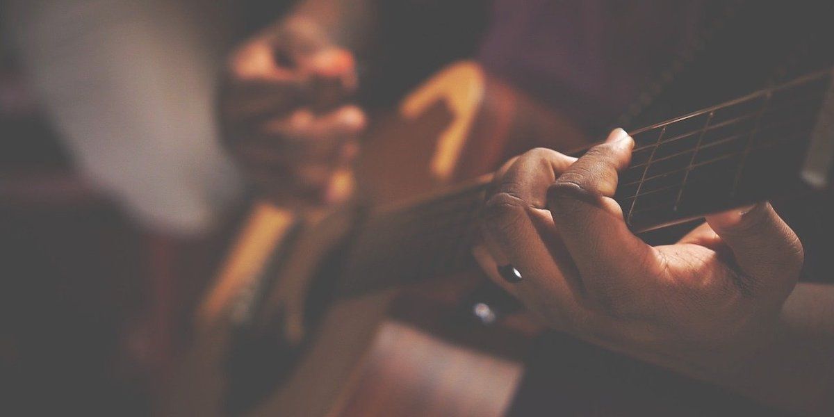 Две руки на акустической гитаре, фокус на левой руке.