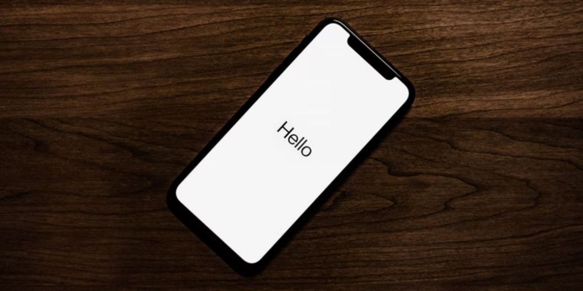 iPhone на деревянной поверхности, экран приветствия 'Hello'